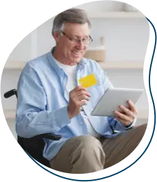 an older man on a wheelchair working on a tablet and smiling